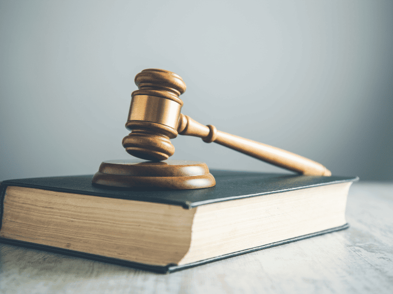 Martelo de juiz apoiado sobre um livro grosso de capa escura.
