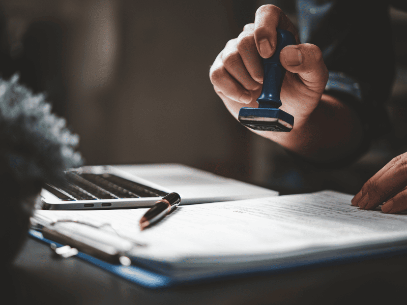 Profissional da cartório carimbando documentos em cima da mesa