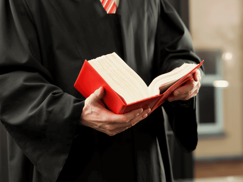 Magistrado segurando um livro jurídico aberto, representando a aplicação da lei e o uso de provas digitais na justiça.