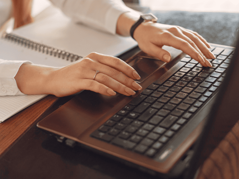 Pessoa utilizando um computador enquanto organiza informações e documentos, representando a preparação de provas digitais para um caso de difamação.