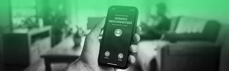 Pessoa segurando um smartphone que exibe uma ligação de um número desconhecido, em um ambiente residencial desfocado ao fundo. A imagem recebe uma sobreposição em tom esverdeado e representa tentativas de contato suspeitas, golpes por telefone e fraudes digitais, destacando os riscos de atender chamadas de remetentes desconhecidos.