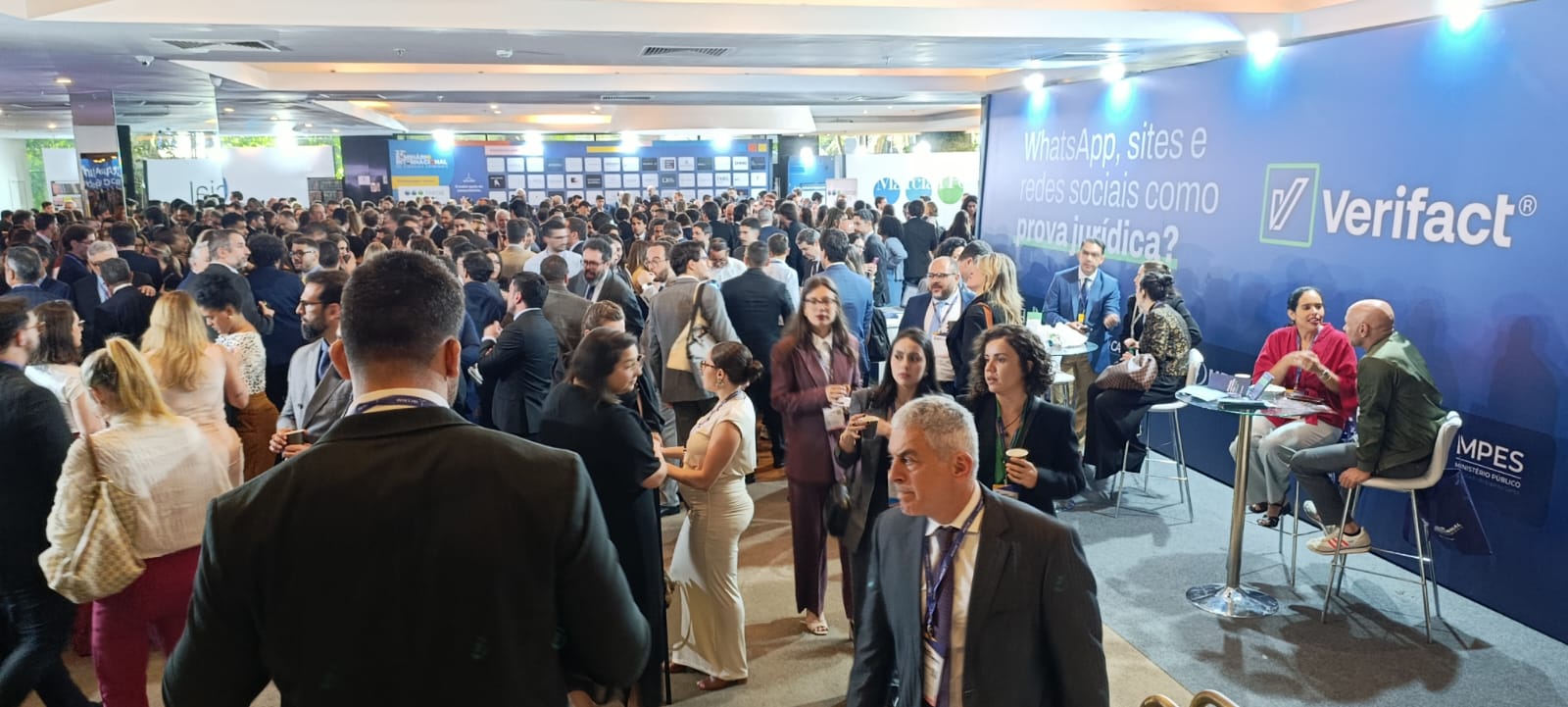 Grande público de advogados e profissionais do direito em momento de networking no IBCCRIM 2026, com o painel da Verifact ao fundo