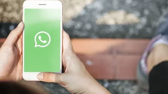 Pessoa segurando smartphone com o aplicativo WhatsApp aberto na tela